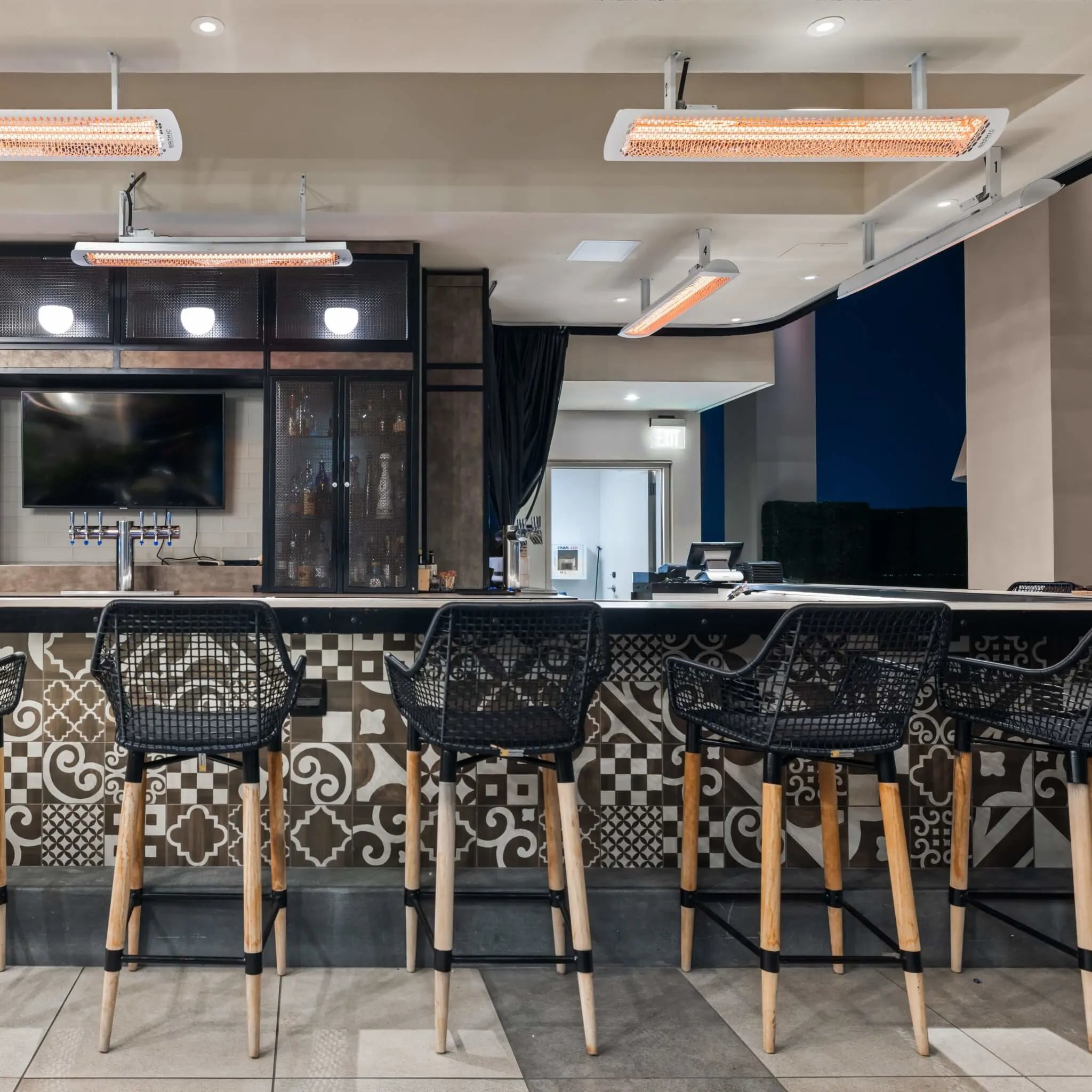 Upscale bar setting with Bromic Tungsten Electric Smart-Heat heaters ceiling-mounted to provide even heat coverage, creating a cozy and inviting environment for guests.