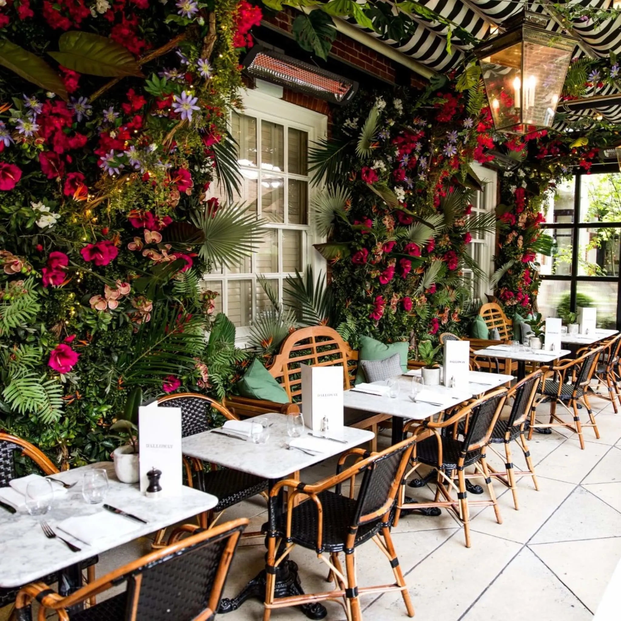 Lush floral-covered restaurant terrace with Bromic Tungsten Electric Smart-Heat heaters mounted overhead, adding comfort and elegance to a stylish London dining setting.
