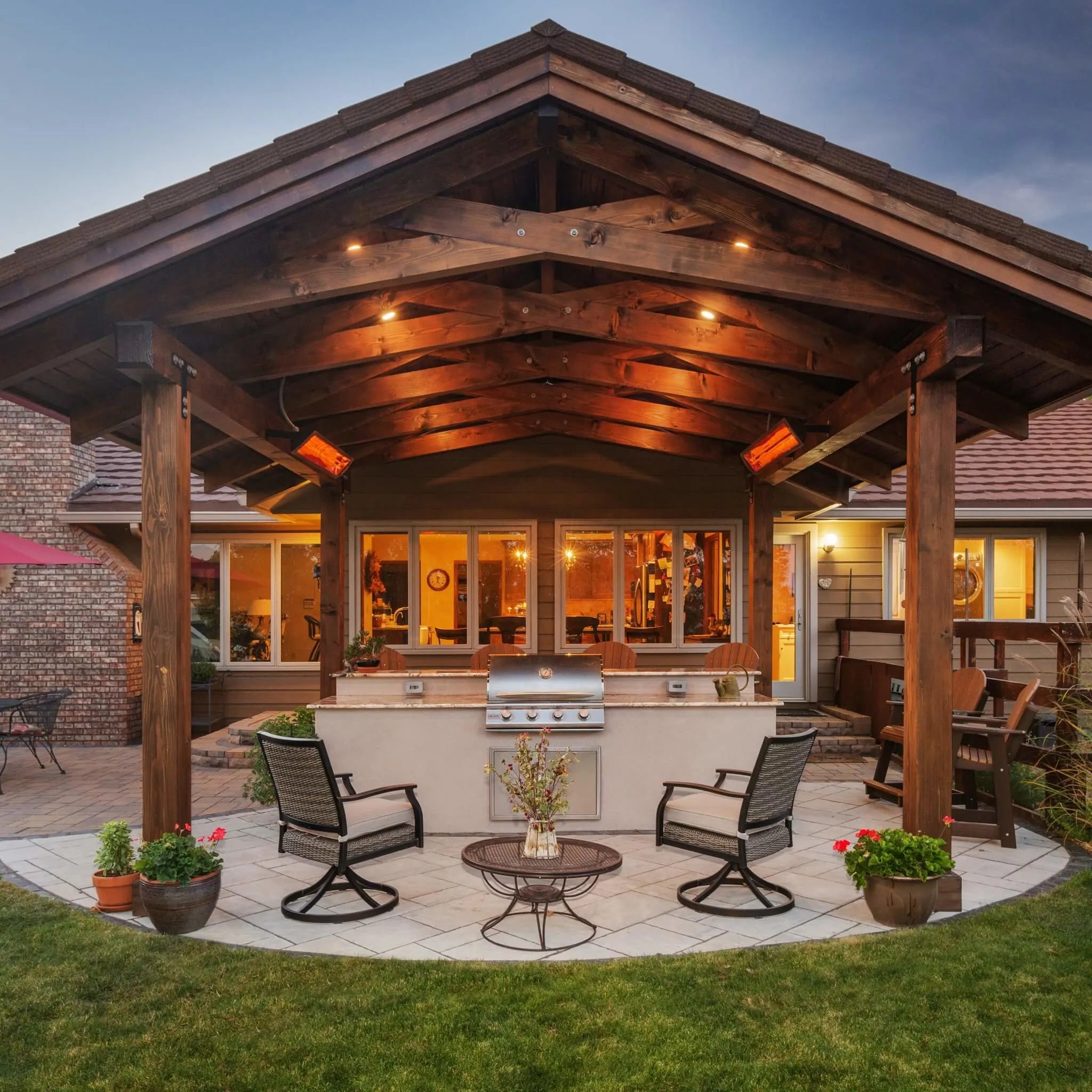 Backyard entertaining space with a rustic wood pergola and Bromic Tungsten Electric Smart-Heat heaters, keeping the outdoor kitchen and seating area comfortably warm.
