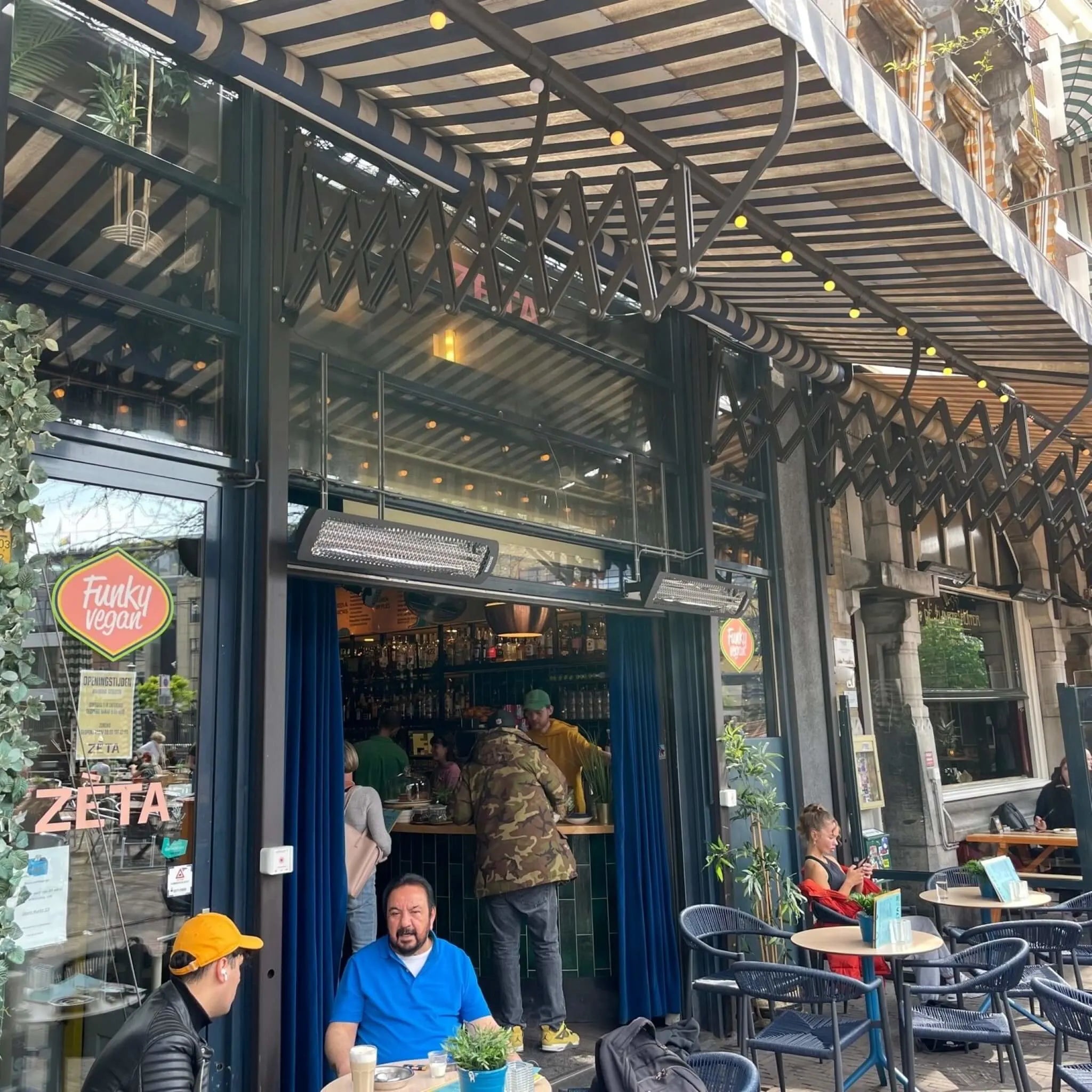 Restaurant patio entrance with Bromic Tungsten Electric Smart-Heat heaters wall-mounted above a striped canopy, keeping cafÃ© guests comfortable while dining outdoors.