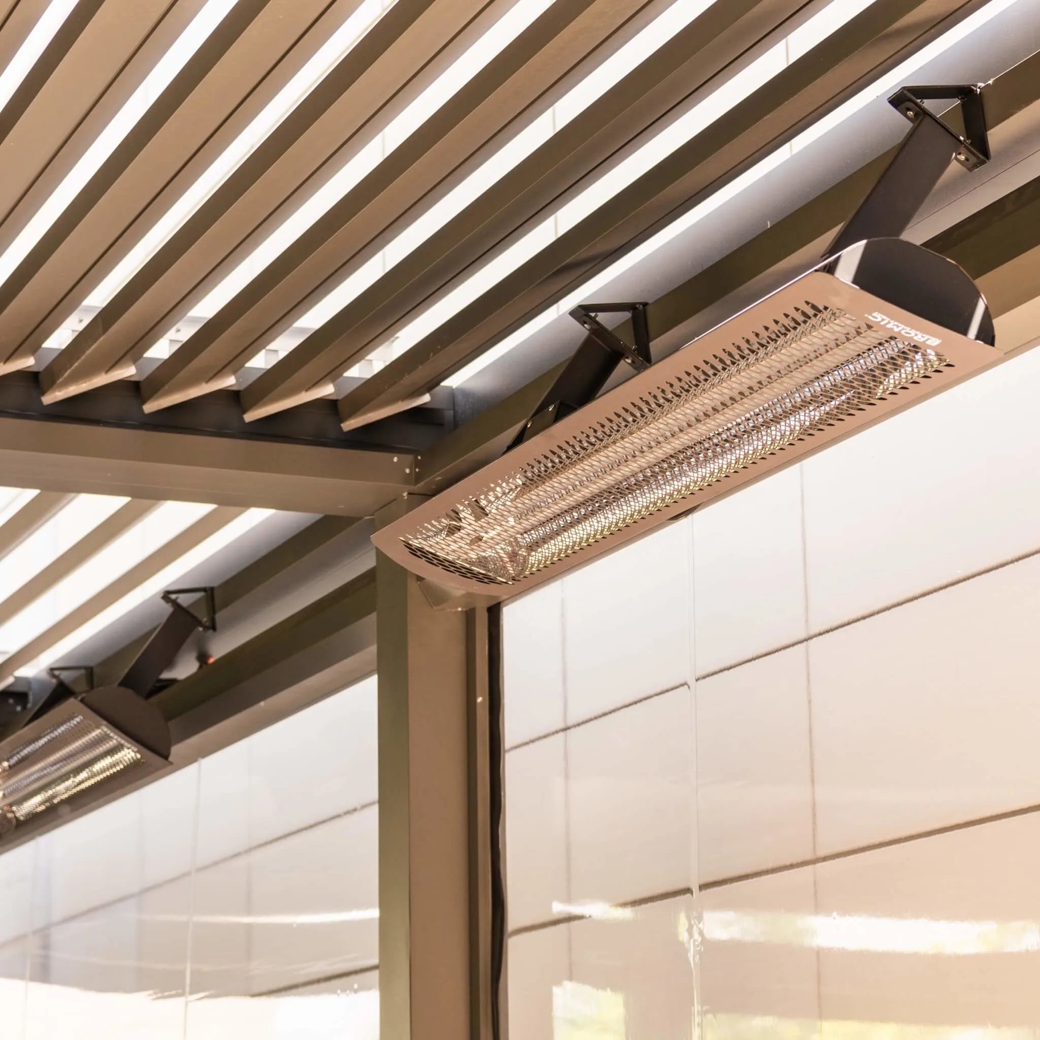 Close-up of Bromic Tungsten Electric Smart-Heat heater mounted under a sleek pergola structure, highlighting its durable design and infrared glow for commercial or residential outdoor use.