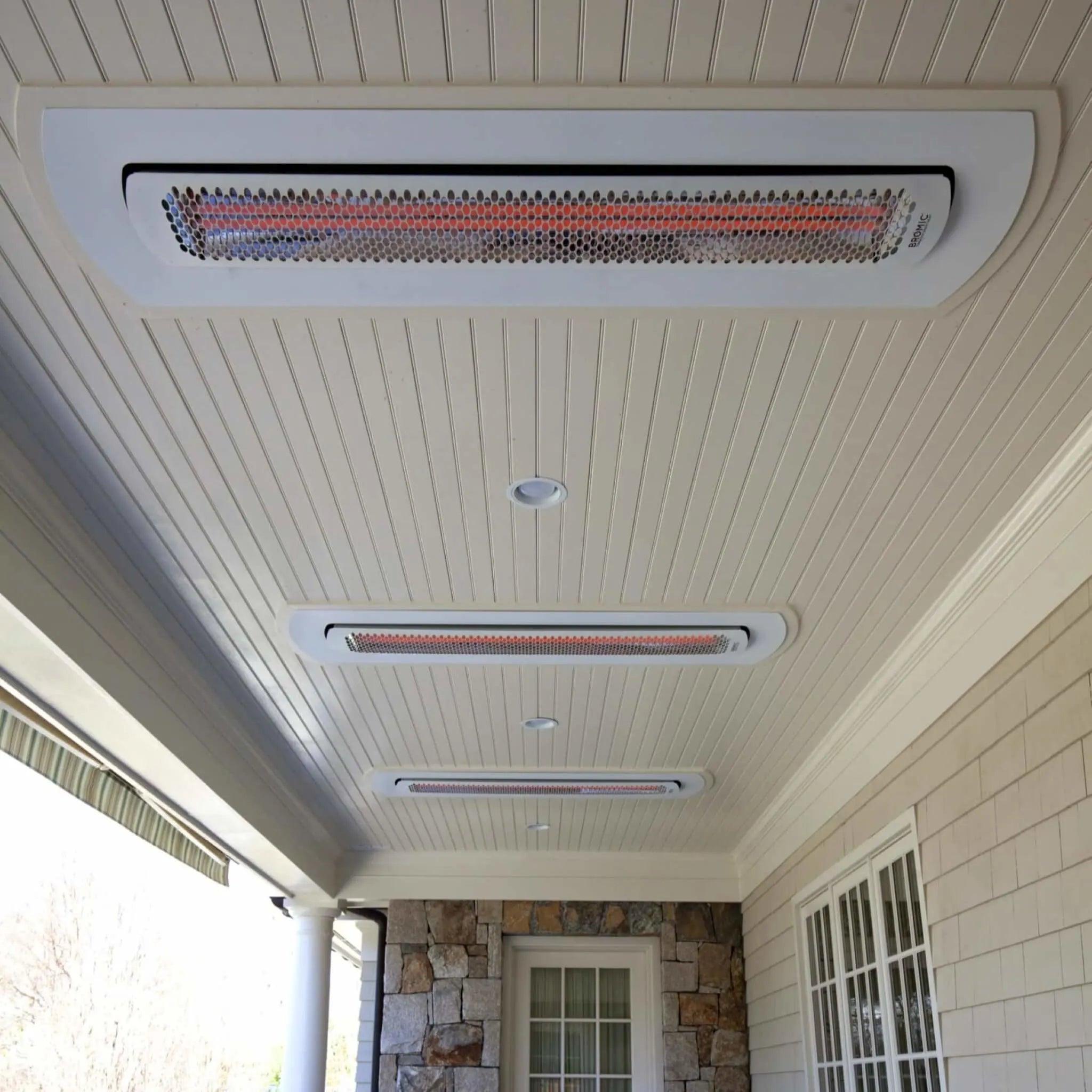 Covered porch with multiple Bromic Tungsten Smart-Heat heaters mounted in white recessed kits, blending seamlessly into the ceiling to provide discreet radiant warmth.